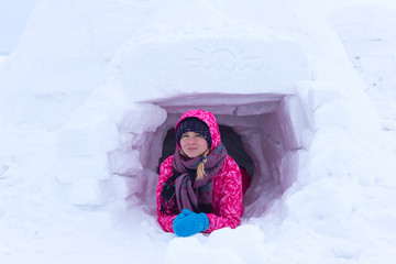 Young woman builds snow Igloo with snow blocks. Winter vacation. Winter and new year holidays
