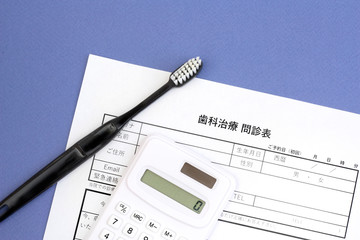 歯の治療の問診票と歯ブラシ・電卓、歯医者の予約