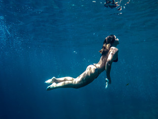 Fototapeta na wymiar Woman swimming underwater on a blue sea and clear water with good visibility for snorkeling.