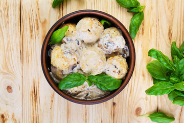 Meatballs with cream and mushrooms on wooden background