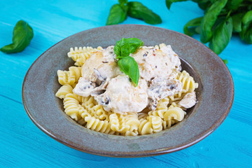 Meatballs with fusilli, cream and mushrooms on wooden background