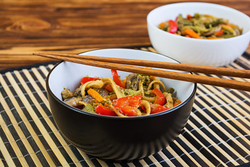 Vegetable stir fry with noodles on wooden background