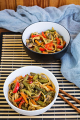 Vegetable stir fry with noodles on wooden background