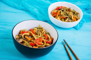 Vegetable stir fry with noodles on wooden background