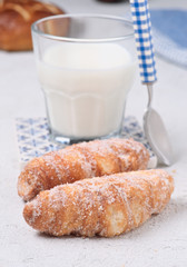 glass of milk with sugary croissants and sweet rolls on white textured background