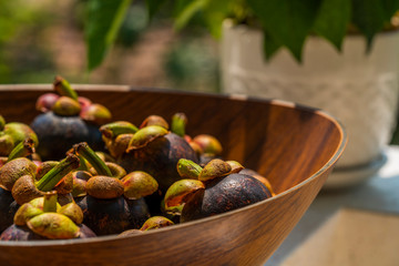 A wooden bowl full of whole ripe mangosteens 