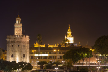 Fototapeta na wymiar The Torre del Oro (English translation: Golden Tower) by night with in the distance the Giralda tower of the cathedral of the city of Seville, Andalusia, Spain