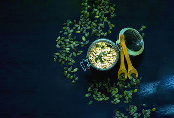 Breakfast of granola and pumpkin seeds in glass jar on blue background. Healthy eating concept. 