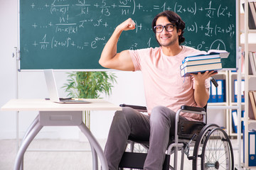 Young handsome man in wheelchair in front of chalkboard 