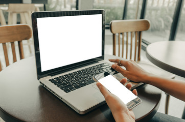 women's hands holding mobile phone and computer laptop