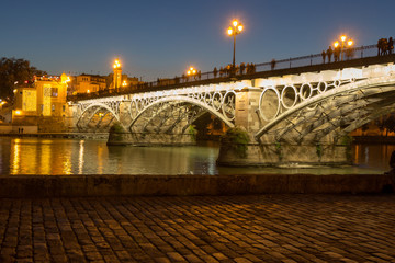 Sevilla, Andalusia, Spain - 04/01/2019 - puente de Isabel II (English translation: Isabel II Bridge) with reflections in the Guadalquivir river during blue hour