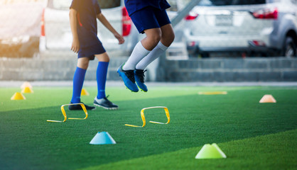 young boy soccer player Jogging and jump between marker and yellow hurdles