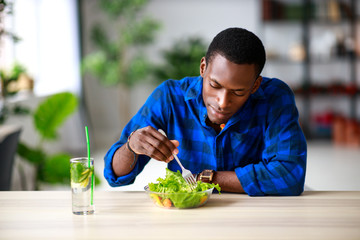 healthy eating. happy young black man eating salad in  morning in kitchen.