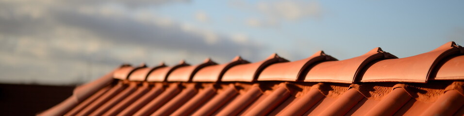 Dächer vom Dachdecker mit rotem Dachziegel Dachfirst. Dachpfannen auf Stadt Haus Neubau mit textfreiem Abendrot Himmel im Hintergrund. - obrazy, fototapety, plakaty