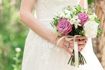 Bride with a wedding bouquet of roses at the ceremony in a white lace dress