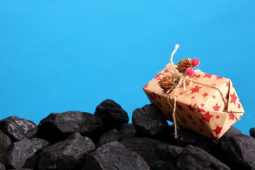 The package with the wrapped gift lies on a heap of black coal.
