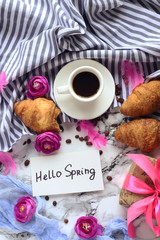 white coffee Cup with Hello Spring text and croissants on marble table. view from the top.flat lay