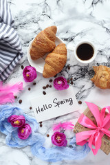 white coffee Cup with Hello Spring text and croissants on marble table. view from the top.flat lay