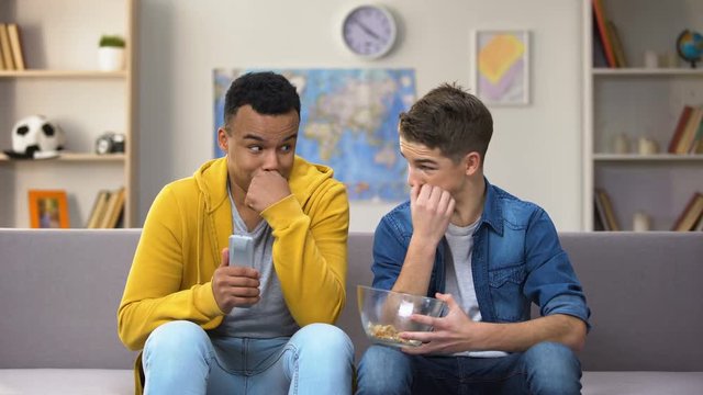 African-American and Caucasian friends watching adult content feeling ashamed