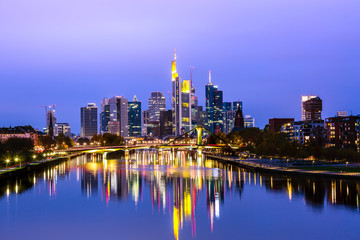 Fototapeta na wymiar Panoramic view cityscape skyline of business district with skyscrapers and mirror reflections in the river Main during sunset blue hour, Frankfurt am Main. Hessen, Germany