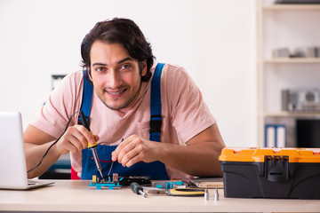 Young male contractor repairing computer  