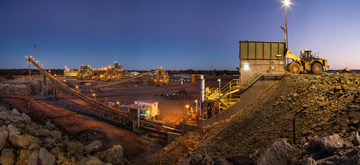 Bulldozer loading rocks into the crusher within the copper mine head at dusk in NSW Australia