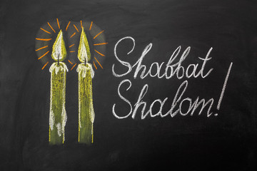 Jewish greetings Shabbat Shalom and candles painted on a chalkboard. May you dwell in completeness...