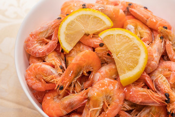 tasty boiled tiger prawns with lemon slices on a white plate. close up