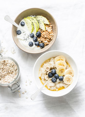 Varied breakfast - yogurt with granola and fruit, vegetarian oatmeal with fruit and berries on a light background, top view