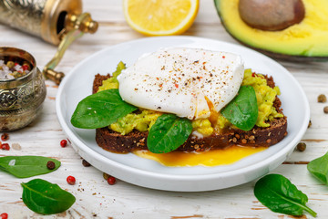  Rye Bread Toast with coriander, Poached Egg with Green Salad spinach , Avocado (guacamole), lemon and spices. Gourmet sandwich. Healthy Breakfast. Selective focus