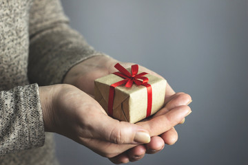 Woman holding a gift box with a red ribbon