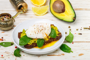  Rye Bread Toast with coriander, Poached Egg with Green Salad spinach , Avocado (guacamole), lemon and spices. Gourmet sandwich. Healthy Breakfast. Selective focus