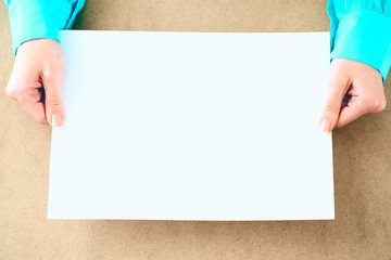 Blank paper in woman's hands waiting for idea or advertising lettering.