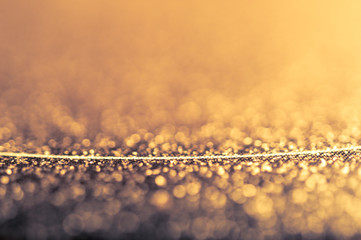 Abstract shiny golden background with bokeh and thin line. Glitter glowing texture pattern. 