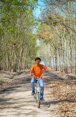 Obraz premium Asian man biking on trail of the rubber forest