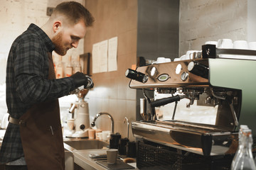 Barista cleaning the portafilter on a shiny espresso machine at the cafe. Bartender is cleaning the holder of the coffee machine at the coffee shop.