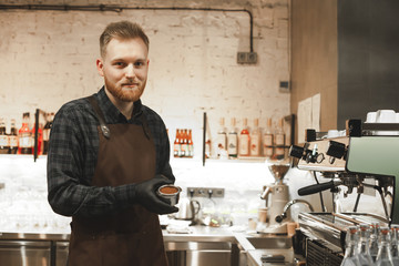 Smiling bearded coffee shop owner is ready to prepare coffee with a coffee machine. Cheerful cafe...