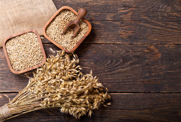 Obraz na płótnie Canvas ears of oat and grains on wooden table