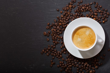 cup of coffee and coffee beans on dark background