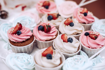 Tasty pink cupcakes close up with strawberries and berries on a white plate