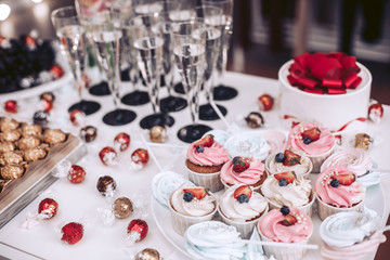 Festive table with delicious cupcakes and glasses of champagne.