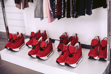 Beautiful red women's sneakers on the white shelf of a shoe store.