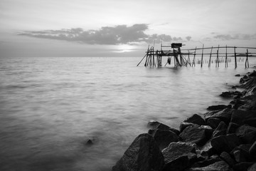 Wooden Jetty with the rocky seaside during sunset. Long Exposure Black and White