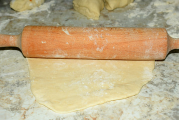 rolling out the dough with a wooden rolling pin