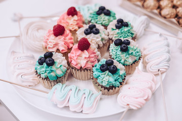 Tasty cupcakes with berries on a white plate.