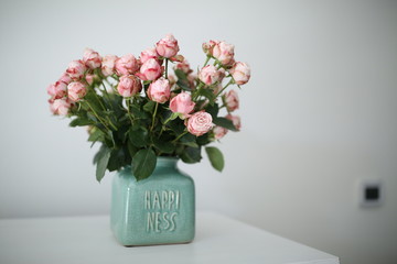 Beautiful pastel pink roses in a shabby chic crackled vase with the word happiness on it