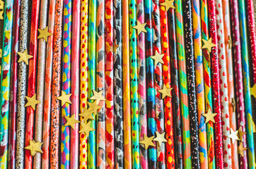 Colorful painted sticks with golden confetti stars bright vivid abstract background top view