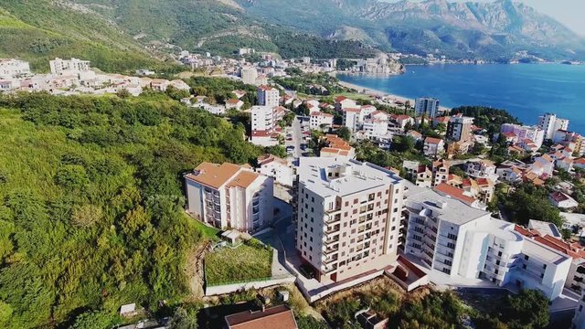 Budva with a bird's eye view. Becici. Drone takes pictures from a height. In the lens of the sea, sky, houses in the old style. Resort town with brown roofs.  Modern hotels by the sea. Port 