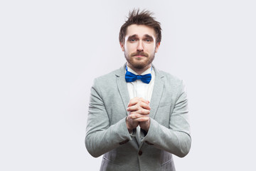I am sorry, please forgive me. sad handsome bearded man in casual grey suit and blue bow tie...