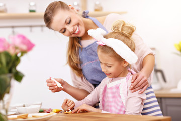Mother and daughter preparing Easter cookies in the kitchen